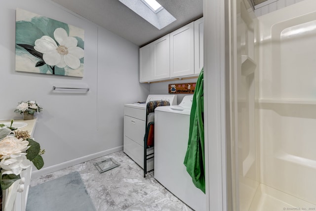 clothes washing area featuring a skylight, a textured ceiling, baseboards, and washer and dryer