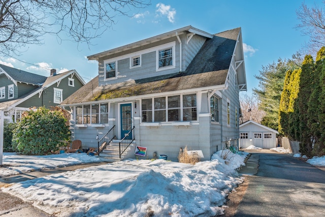 view of front facade featuring entry steps, roof with shingles, an outdoor structure, and a detached garage