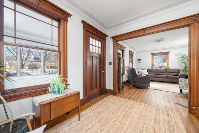 entrance foyer with a wealth of natural light, baseboards, crown molding, and light wood finished floors