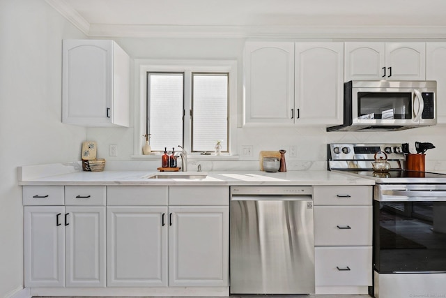 kitchen with white cabinets, ornamental molding, light stone countertops, stainless steel appliances, and a sink