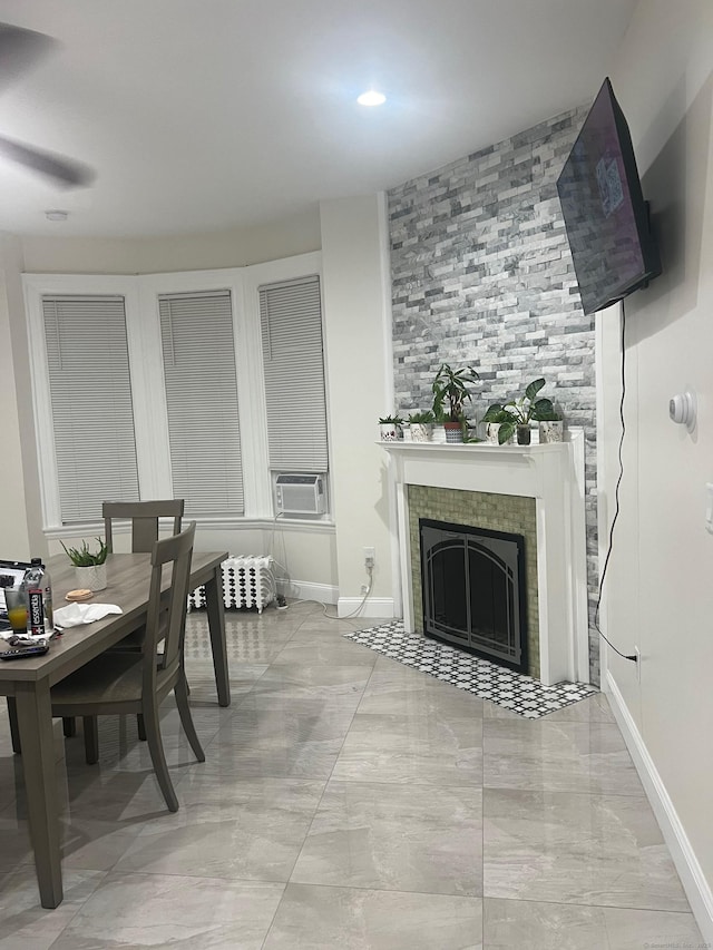 dining area featuring baseboards, cooling unit, and a tile fireplace