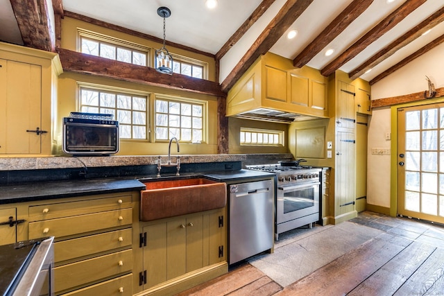 kitchen featuring vaulted ceiling with beams, dark countertops, appliances with stainless steel finishes, and a sink