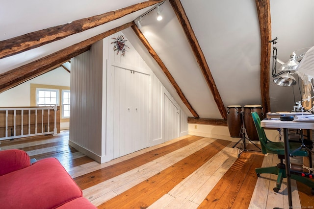 additional living space with vaulted ceiling with beams and wood-type flooring