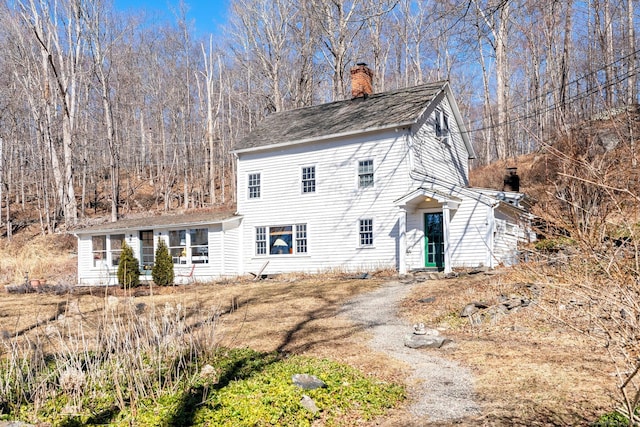 view of front of home with a chimney and dirt driveway