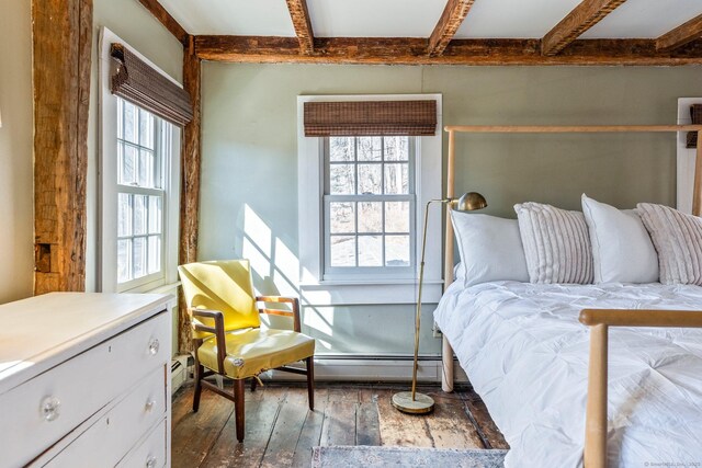 bedroom featuring a baseboard heating unit, beam ceiling, multiple windows, and hardwood / wood-style flooring