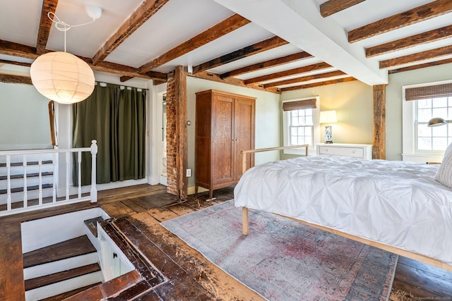 bedroom featuring beam ceiling, wood finished floors, and multiple windows