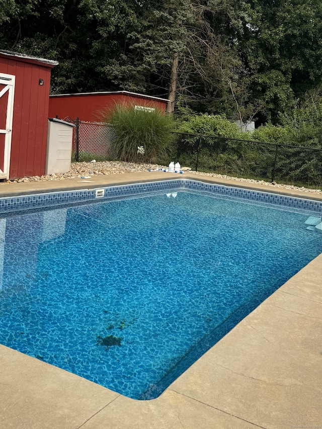 view of swimming pool featuring a storage shed, an outdoor structure, fence, and a fenced in pool