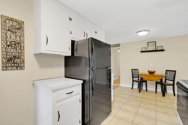 kitchen with electric stove, white cabinetry, freestanding refrigerator, light countertops, and light tile patterned floors