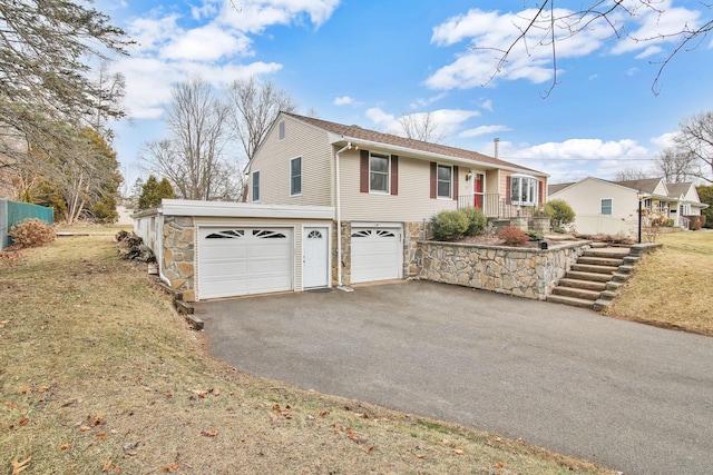 single story home with stone siding, driveway, and a garage