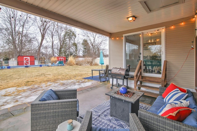 view of patio / terrace with an outbuilding, fence, an outdoor living space with a fire pit, a storage unit, and a grill