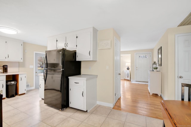 kitchen with light tile patterned floors, white cabinetry, light countertops, and freestanding refrigerator