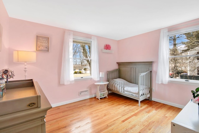 bedroom with light wood-type flooring, multiple windows, and baseboards