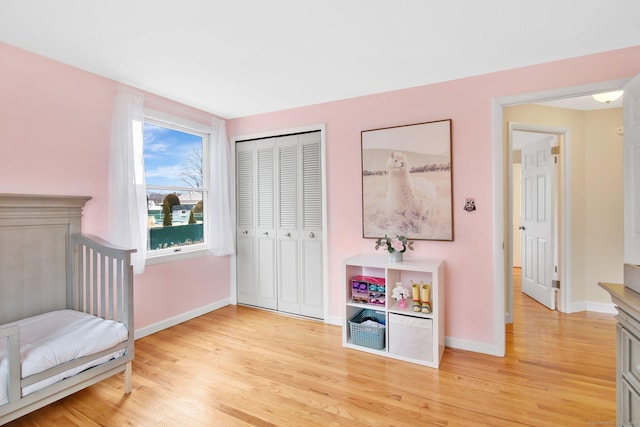 bedroom featuring light wood-style floors, baseboards, and a closet