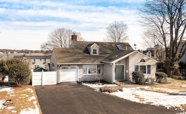 view of front facade with aphalt driveway, fence, a chimney, and an attached garage