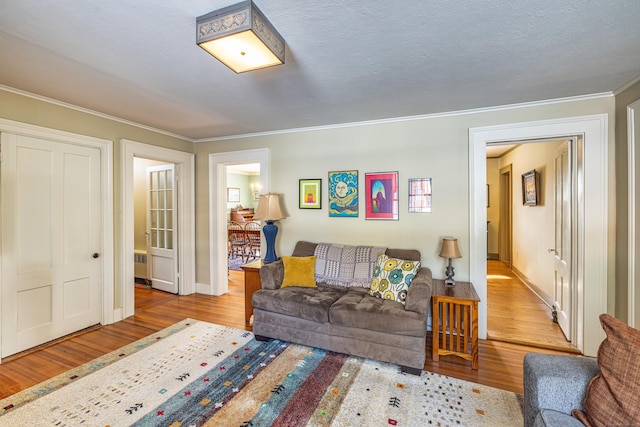 living room featuring baseboards, ornamental molding, wood finished floors, and radiator