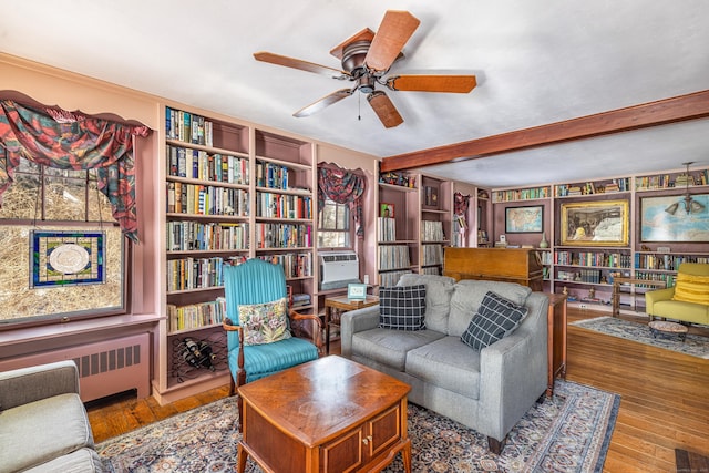living room featuring beam ceiling, cooling unit, radiator heating unit, a ceiling fan, and hardwood / wood-style flooring