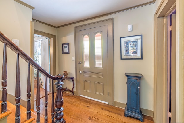 entryway with stairway, baseboards, crown molding, and light wood finished floors