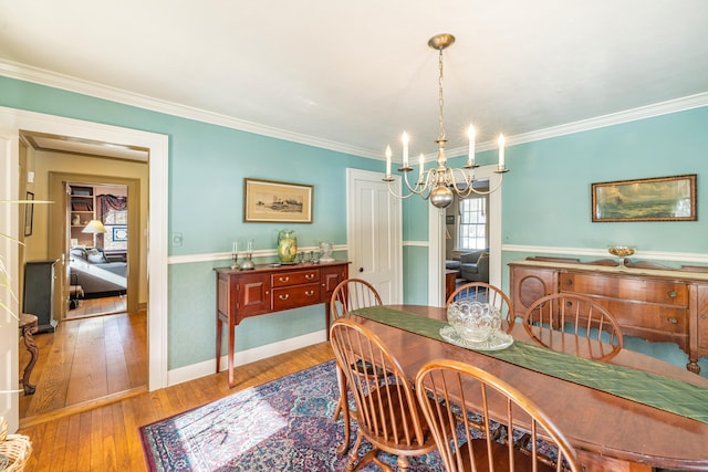 dining space featuring crown molding, baseboards, a notable chandelier, and hardwood / wood-style flooring