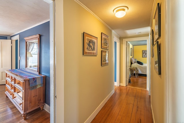 corridor featuring baseboards, ornamental molding, and dark wood-style floors