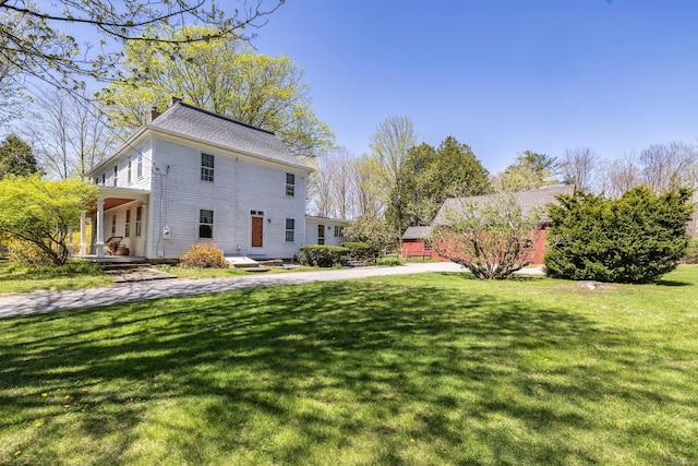 view of property exterior featuring a yard, a chimney, and covered porch