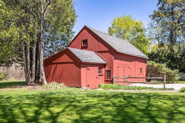 view of barn with fence and a yard