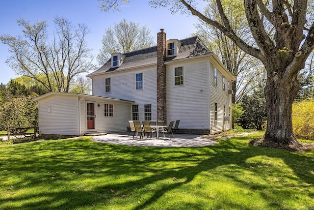 rear view of property featuring a lawn, entry steps, a chimney, and a patio area