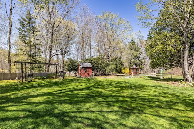view of yard with a gazebo, a storage shed, a fenced backyard, a playground, and an outdoor structure