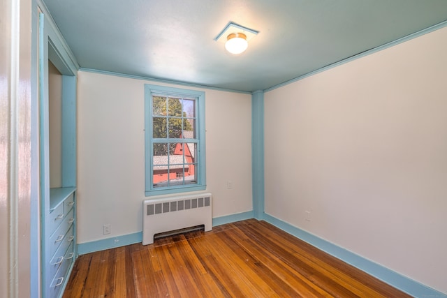 empty room with radiator heating unit, baseboards, and dark wood finished floors