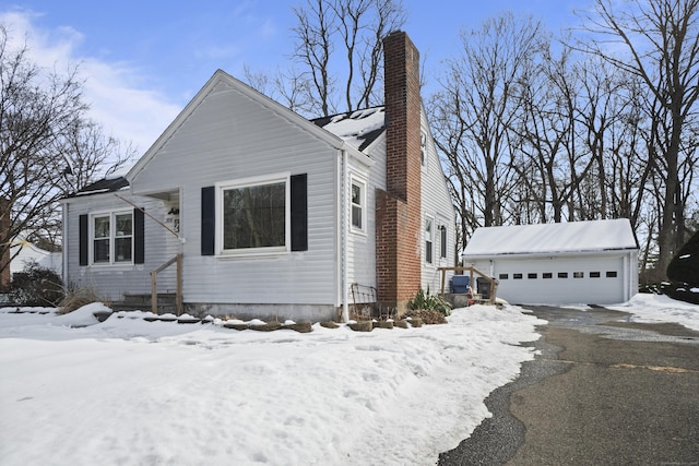 view of front of house with a garage, a chimney, and an outdoor structure