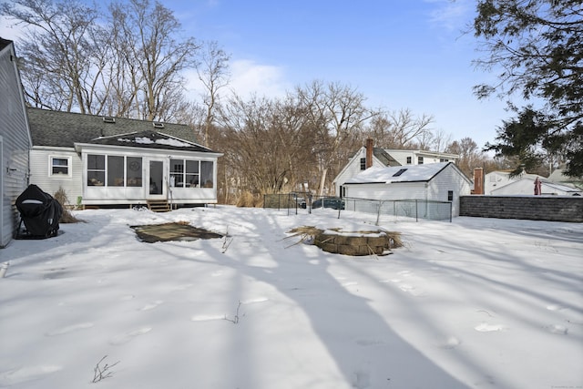 yard layered in snow with entry steps, fence, and a sunroom