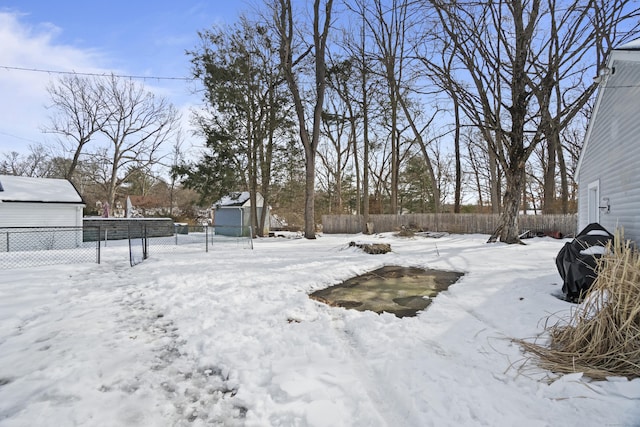 yard covered in snow with a garage and fence