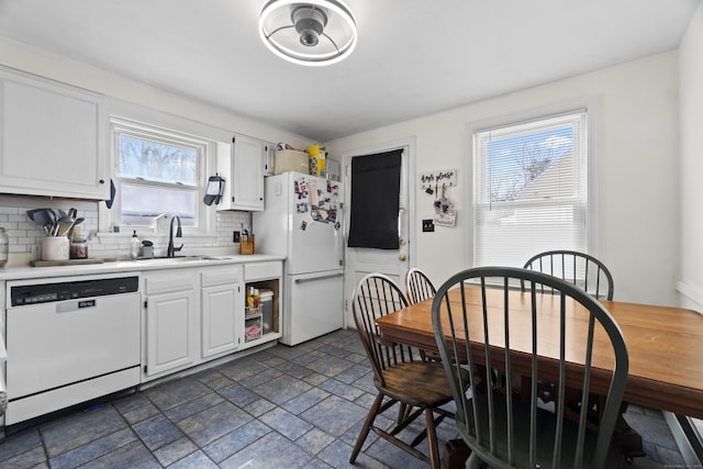 kitchen featuring white appliances, light countertops, stone tile flooring, white cabinetry, and a sink