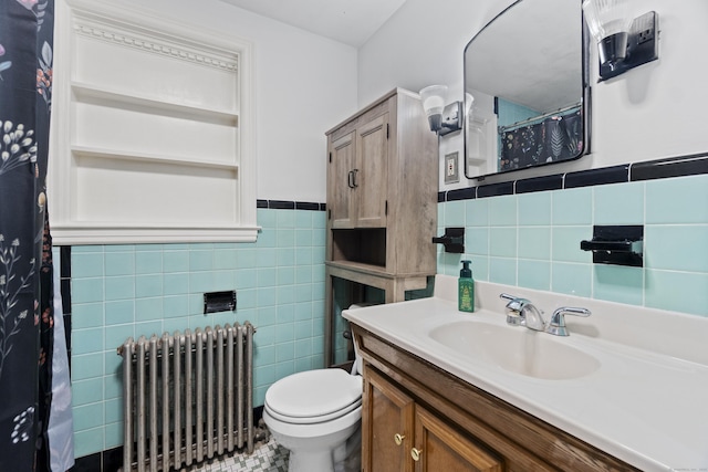 bathroom with a wainscoted wall, tile walls, radiator, toilet, and vanity