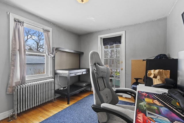 office with light wood-style floors and radiator