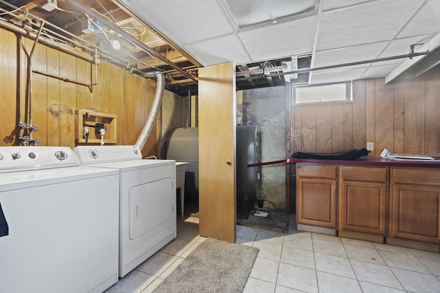 washroom with wood walls, independent washer and dryer, cabinet space, and light tile patterned flooring