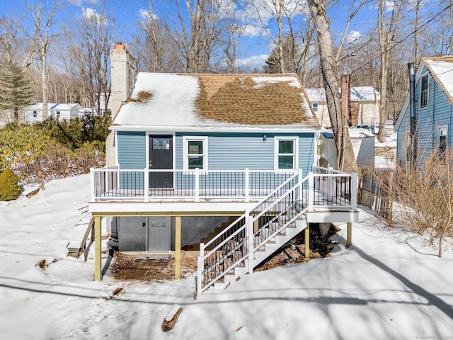 view of front of home with stairway, roof with shingles, and a chimney