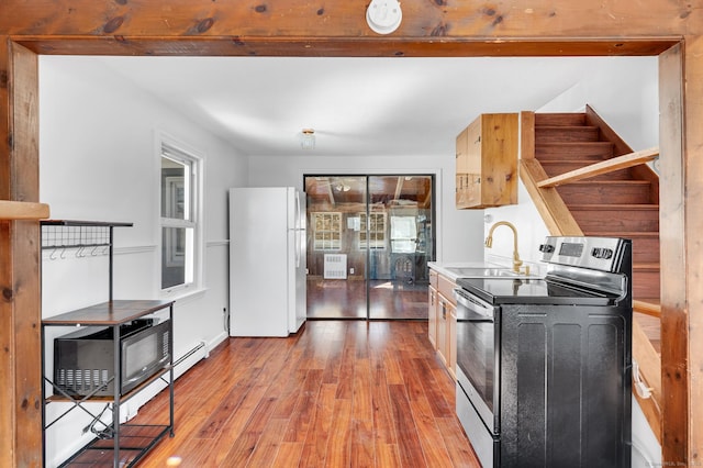 kitchen featuring a sink, light wood-style flooring, electric stove, and freestanding refrigerator