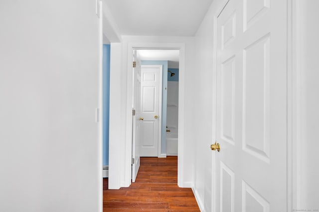 corridor featuring dark wood finished floors and a baseboard radiator