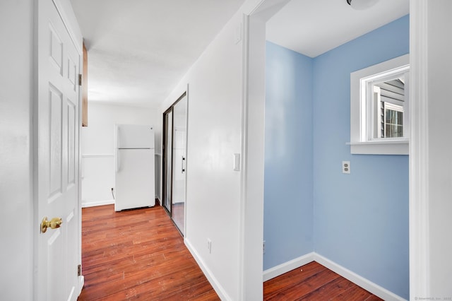 hall with baseboards and wood-type flooring