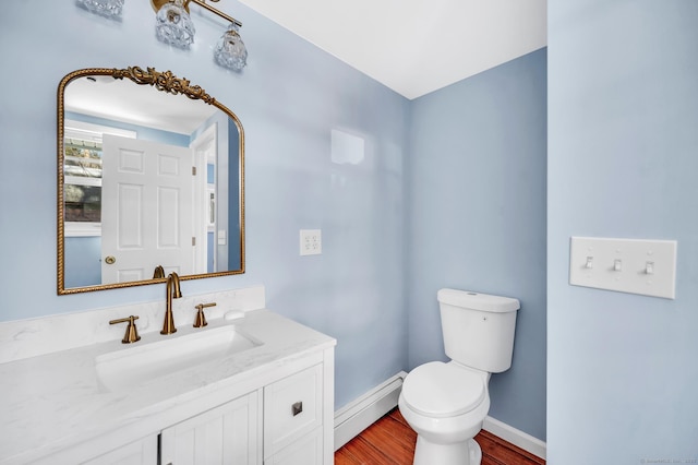 bathroom featuring toilet, a baseboard heating unit, wood finished floors, baseboards, and vanity