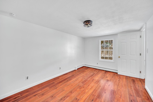 unfurnished room featuring a baseboard radiator, baseboards, and light wood-style flooring