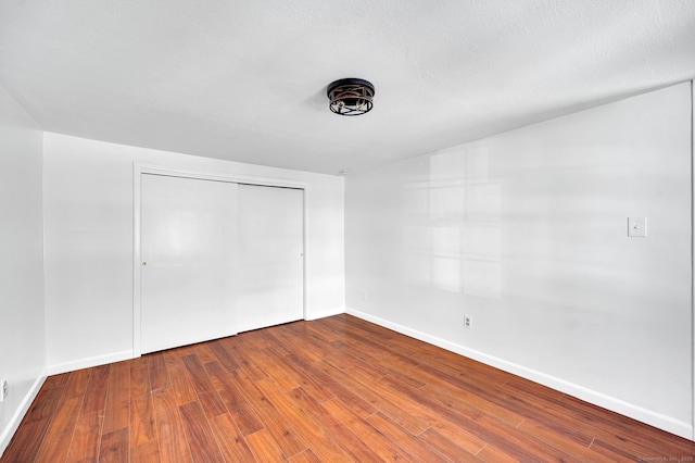 unfurnished bedroom featuring a closet, baseboards, and hardwood / wood-style floors