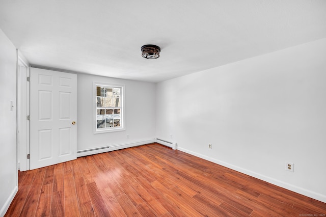 unfurnished bedroom with baseboard heating, baseboards, and wood finished floors