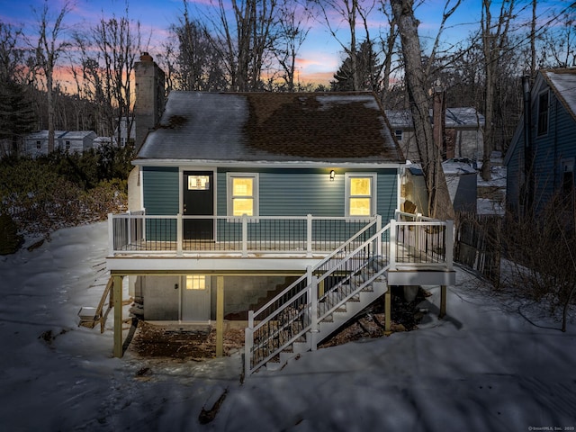 view of front of home featuring stairway, a chimney, and a shingled roof