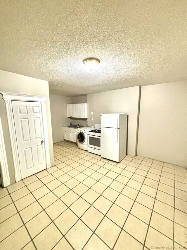 kitchen with a textured ceiling, white appliances, washer / dryer, and white cabinetry