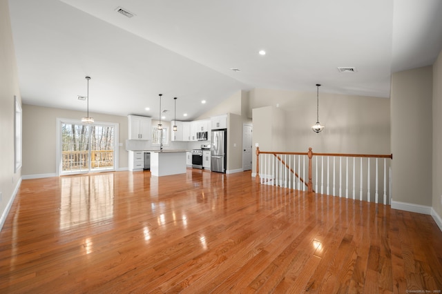 unfurnished living room with lofted ceiling, baseboards, visible vents, and light wood finished floors