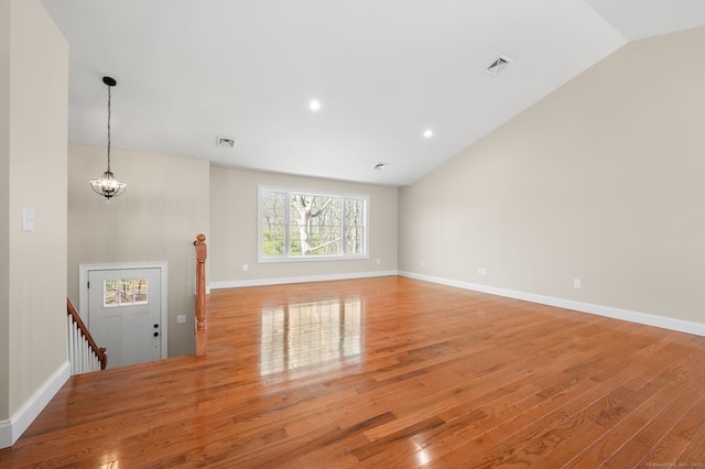 unfurnished living room with light wood-type flooring, visible vents, baseboards, and vaulted ceiling