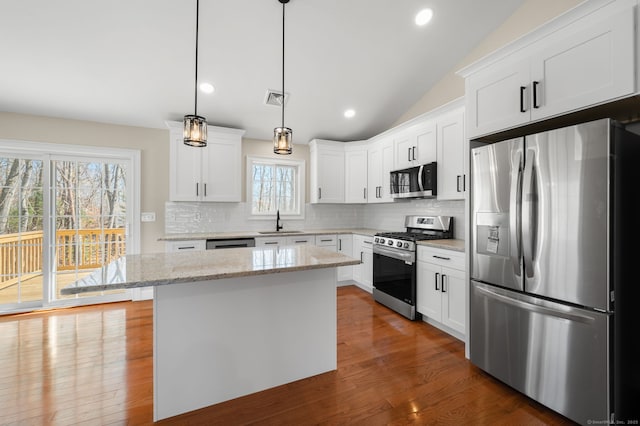 kitchen with visible vents, a center island, decorative backsplash, appliances with stainless steel finishes, and a sink