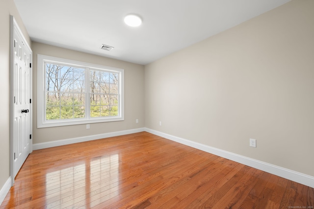 unfurnished room with visible vents, light wood-type flooring, and baseboards