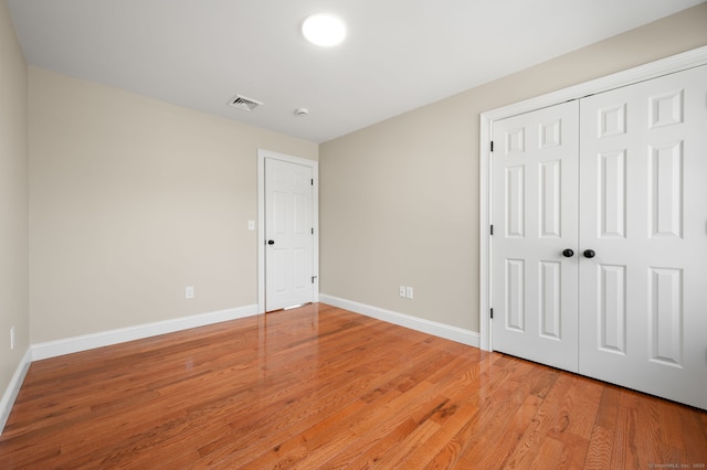 unfurnished bedroom featuring a closet, visible vents, light wood-type flooring, and baseboards